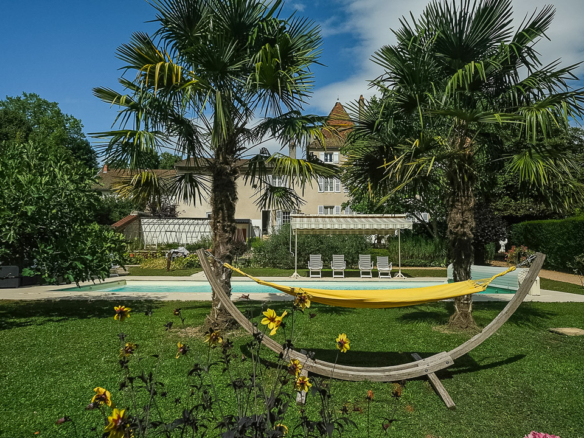Piscine chauffée entourée de palmiers dans le parc arboré d'une maison bourgeoise à La Roche-Vineuse.