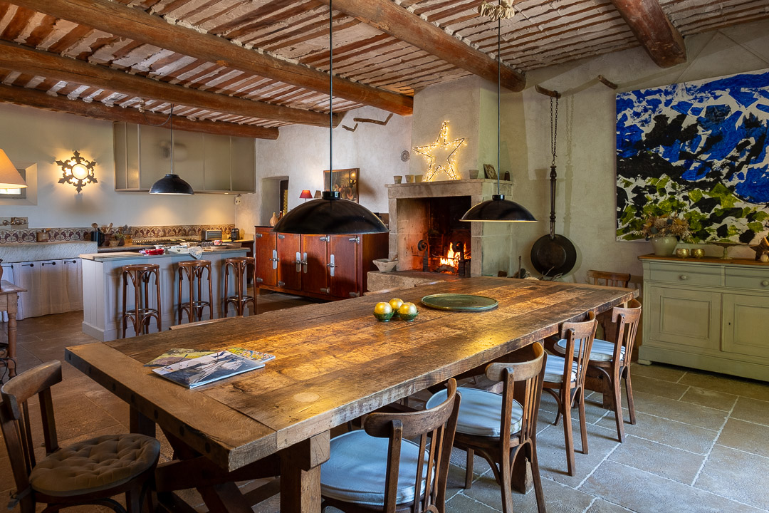 Grande cuisine provençale avec cheminée et table de réception dans un mas de caractère près de L'Isle-sur-la-Sorgue.