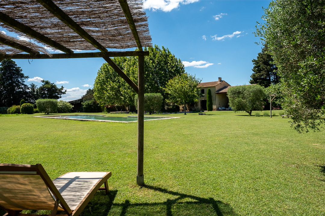 Espaces de détente avec pergolas en canisses autour de la piscine d'un mas provençal dans le Luberon.