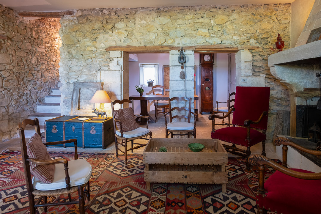 Salon en pierre avec cheminée ancienne dans un mas provençal de caractère près de L'Isle-sur-la-Sorgue.