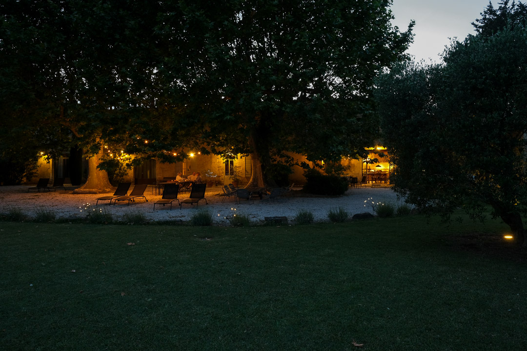 Jardin illuminé au crépuscule devant un mas provençal dans le Luberon.