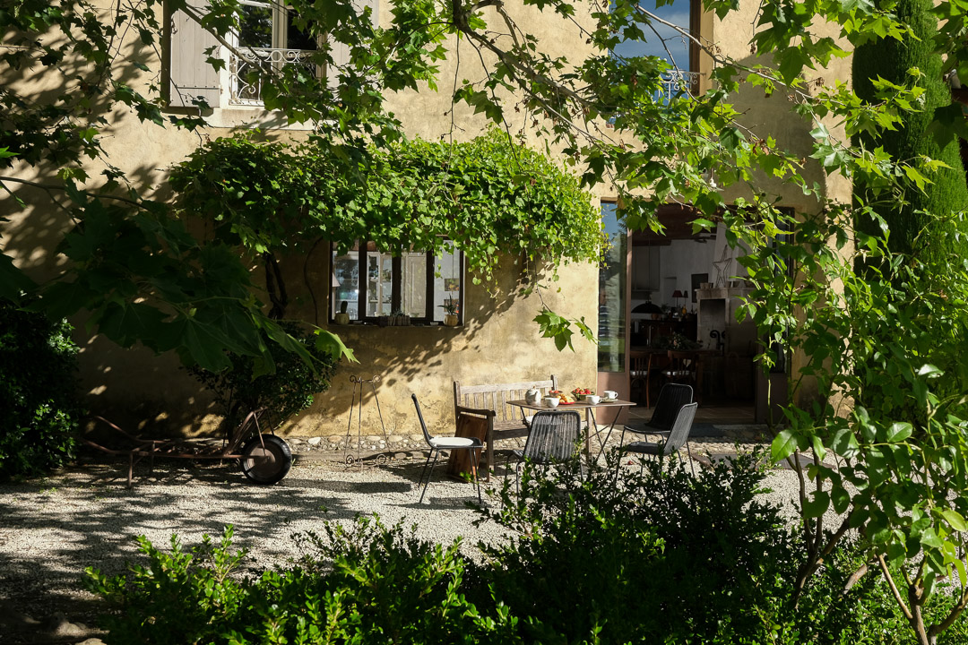 Table dressée pour un petit-déjeuner sous les platanes devant un mas provençal dans le Luberon.