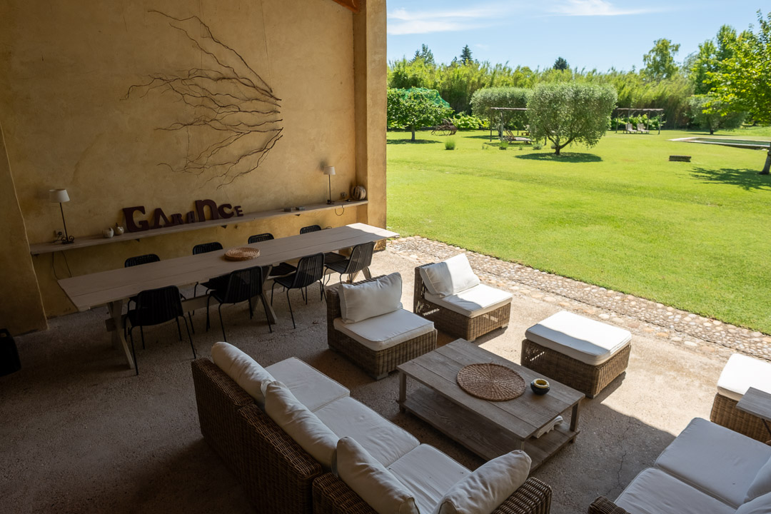 Grand salon extérieur couvert ouvert sur le parc paysager d'un mas provençal près de L'Isle-sur-la-Sorgue.