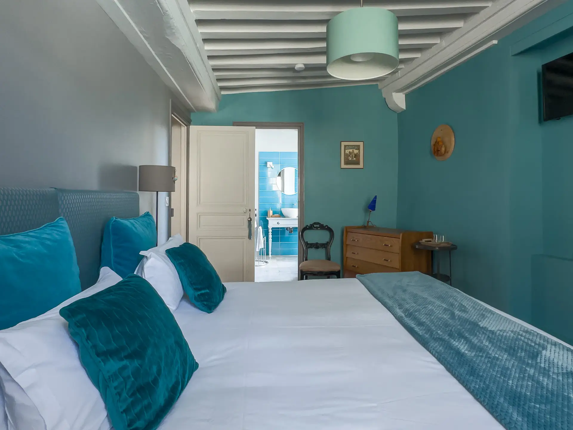 Chambre d’une maison du XVIIe siècle à Charolles avec poutres apparentes et accès direct à la salle d’eau.