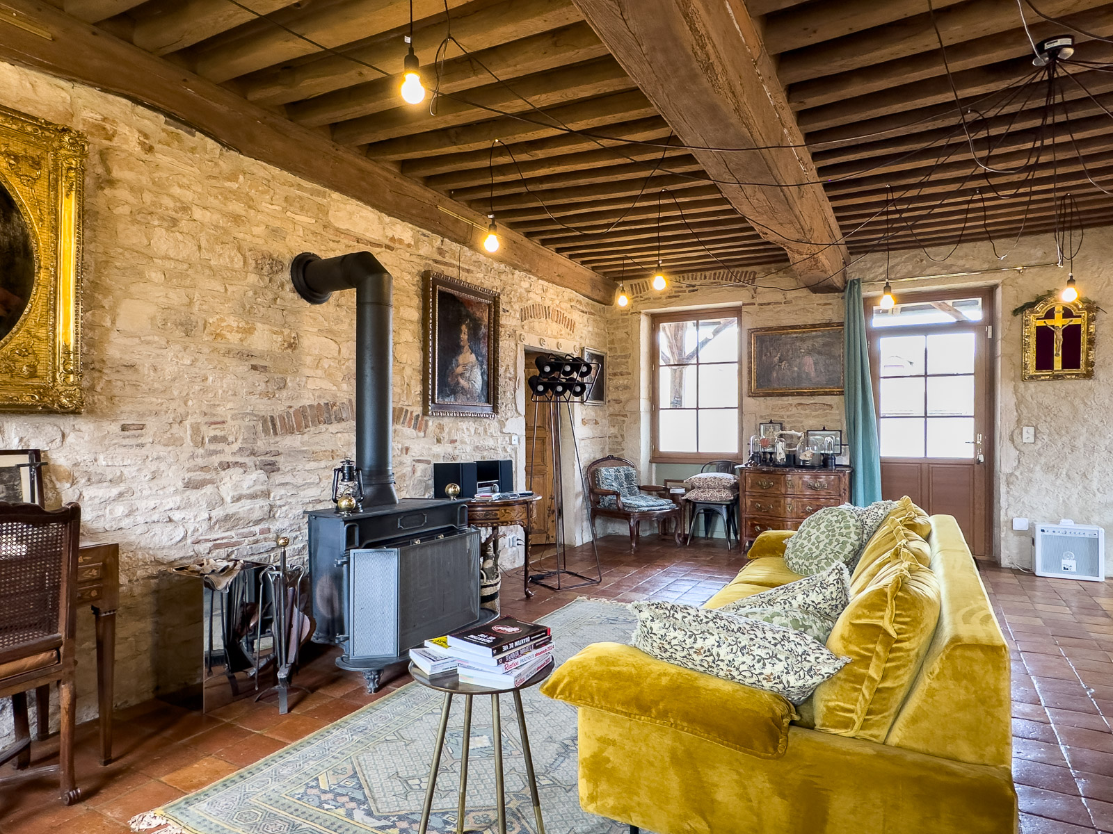 Pièce de vie avec murs en pierre et poêle dans la maison principale en Bourgogne du Sud