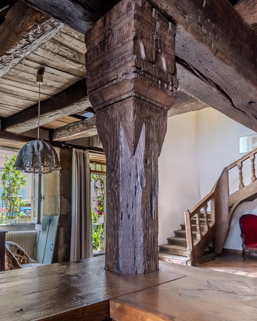 Colonne en bois sculpté supportant une charpente ancienne dans un presbytère du XIVe siècle à Gourdon en Bourgogne du Sud.