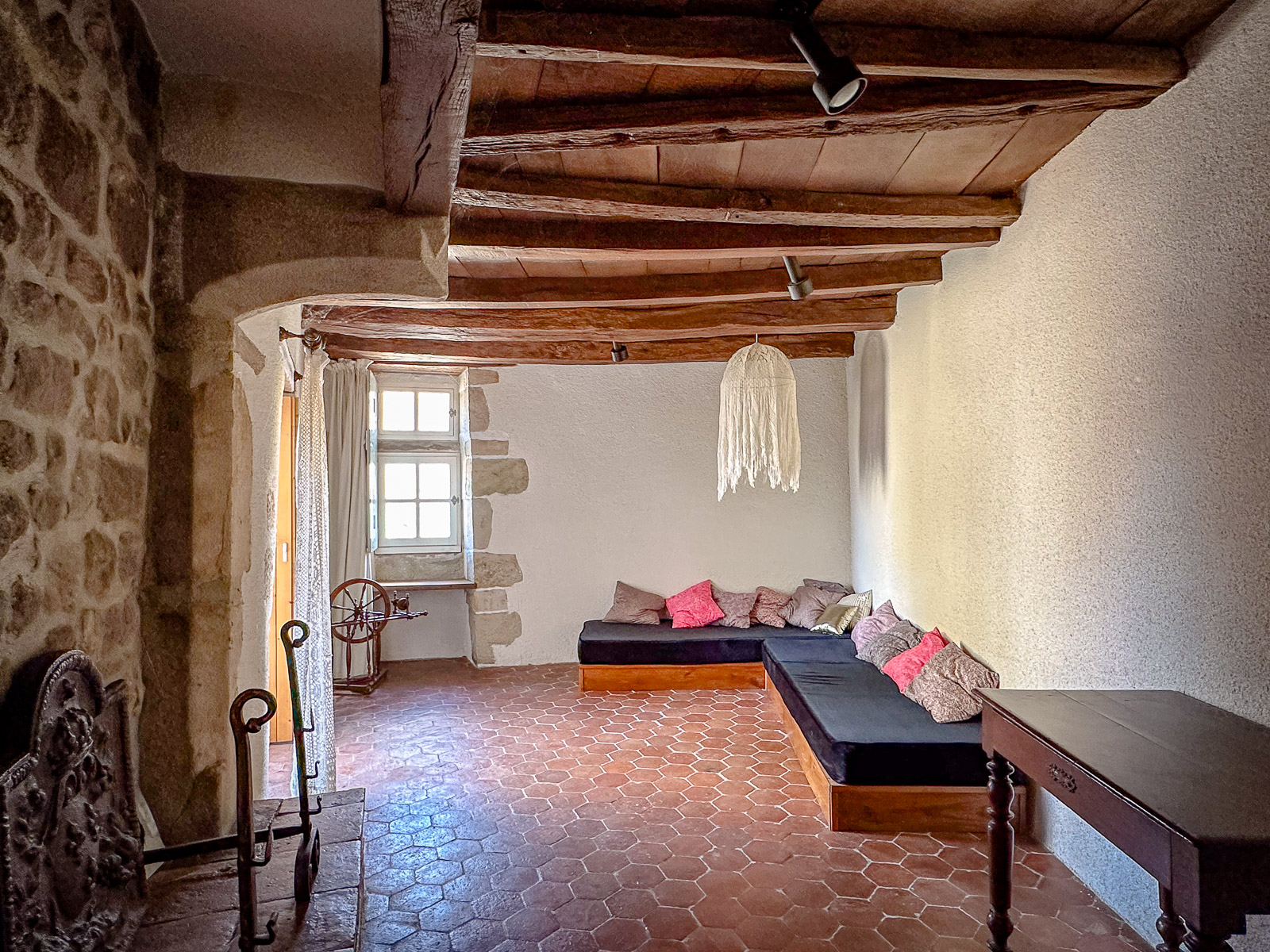 Pièce avec tomettes anciennes et poutres apparentes dans une maison de caractère