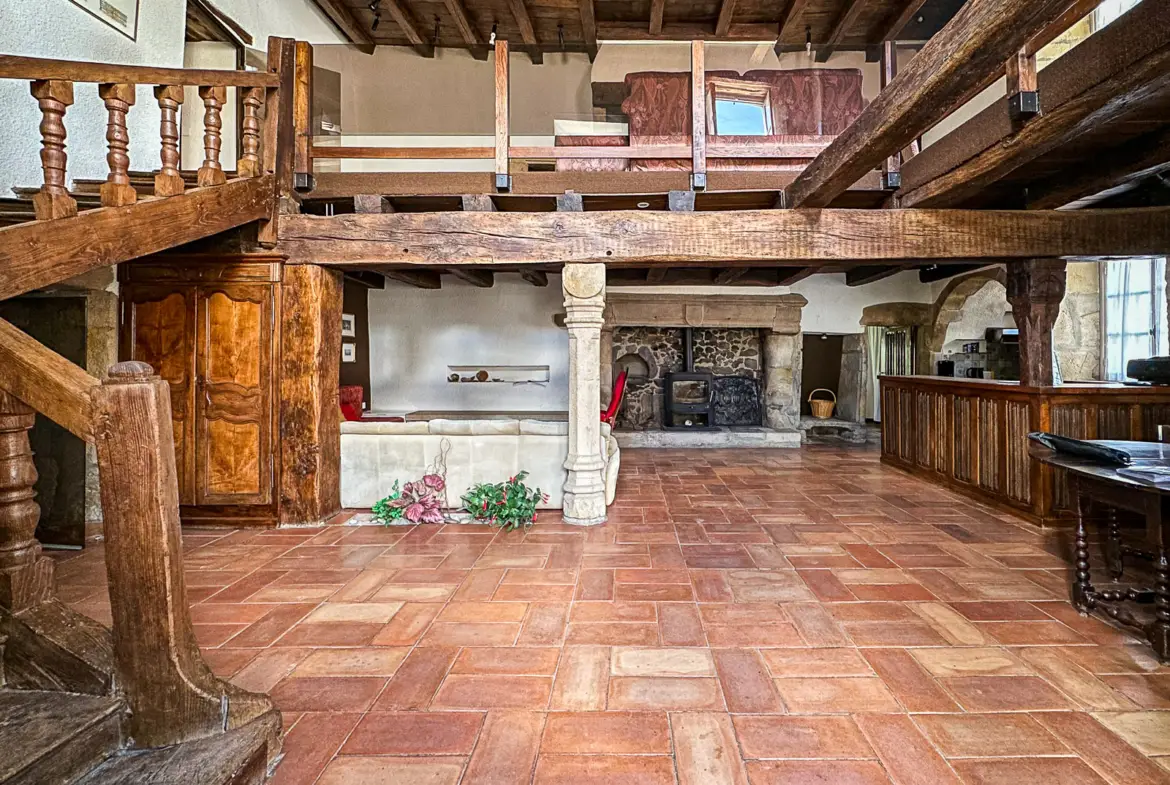 Salon avec poutres anciennes et cheminée en pierre dans une maison médiévale en Bourgogne