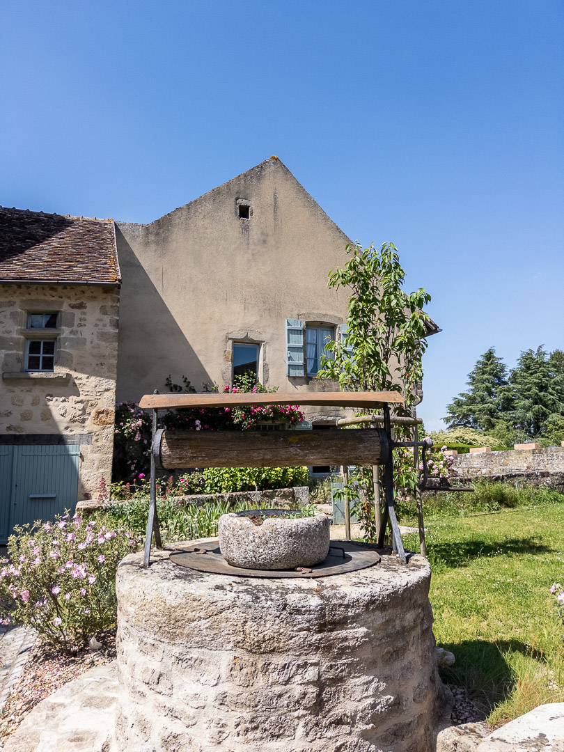 Puits ancien en pierre devant le jardin d'un presbytère du XIVe siècle à Gourdon près de Cluny en Bourgogne du Sud.