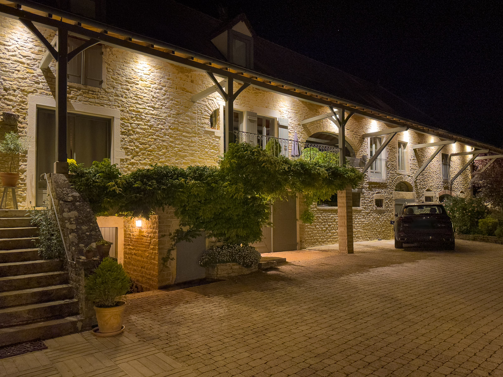 Maison en pierre éclairée de nuit avec galerie couverte et mise en lumière architecturale à Bissy-sur-Fley