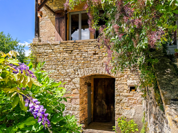 Maison en pierre avec galerie mâconnaise et végétation fleurie proche de Cluny