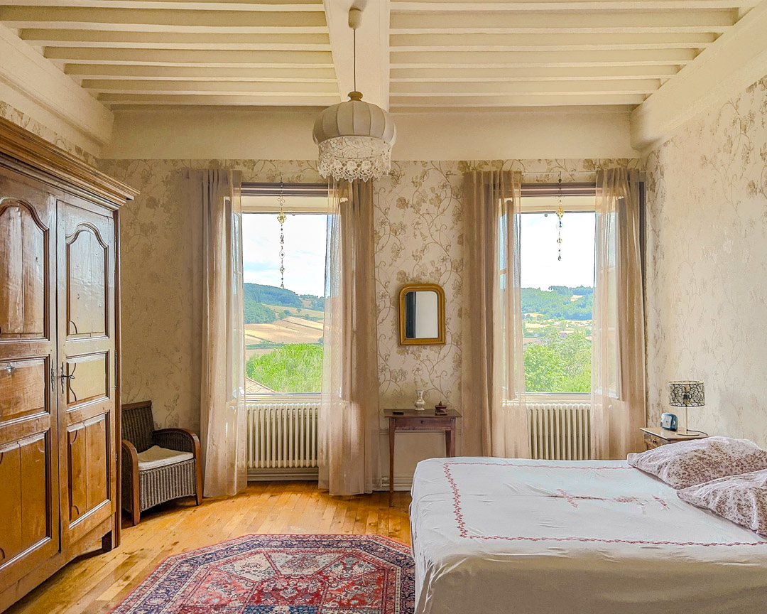 Chambre lumineuse avec vue dominante sur la vallée dans une maison bourgeoise du XVIIIᵉ siècle située dans le Clunisois.