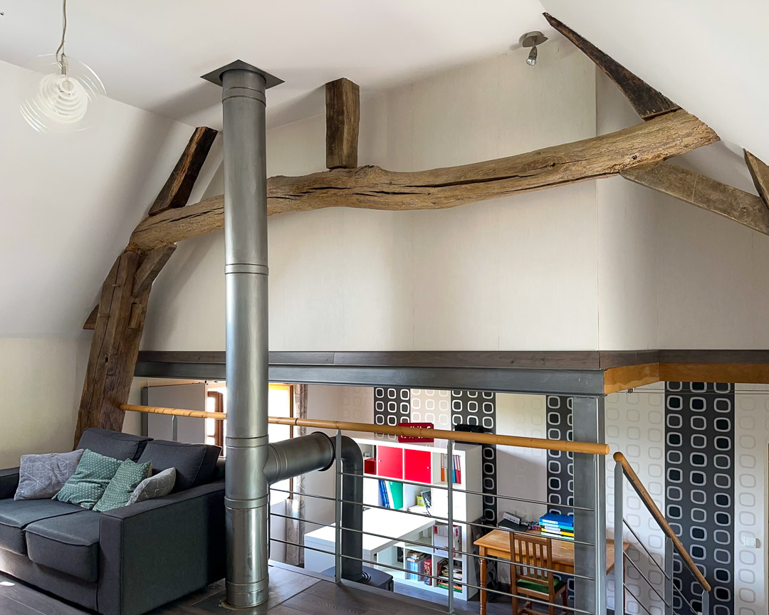 Salon TV aménagé en mezzanine sous charpente apparente dans une maison de caractère entre Cluny et Salornay-sur-Guye.