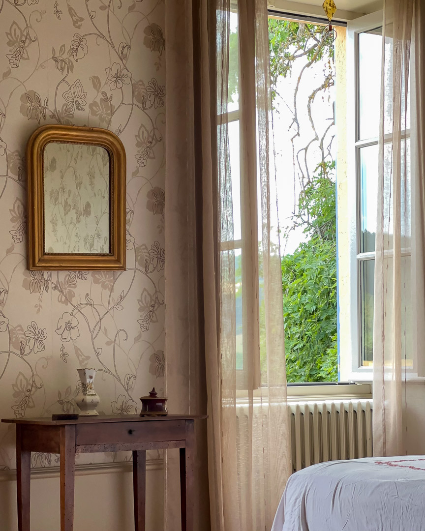 Fenêtre ouverte sur le jardin dans une chambre d'une maison bourgeoise du XVIIIᵉ siècle en Clunisois.