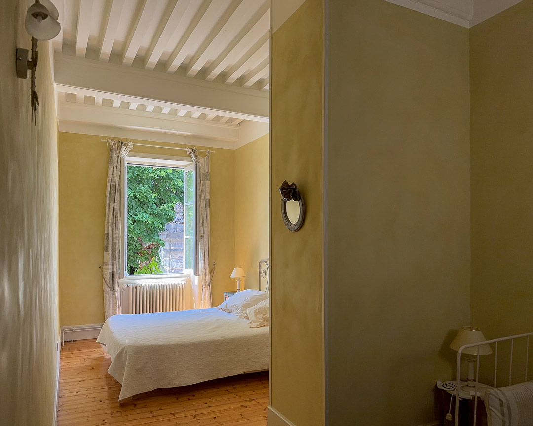 Grande chambre avec plafond à la française et vue sur le jardin dans une maison bourgeoise du XVIIIᵉ siècle en Clunisois.