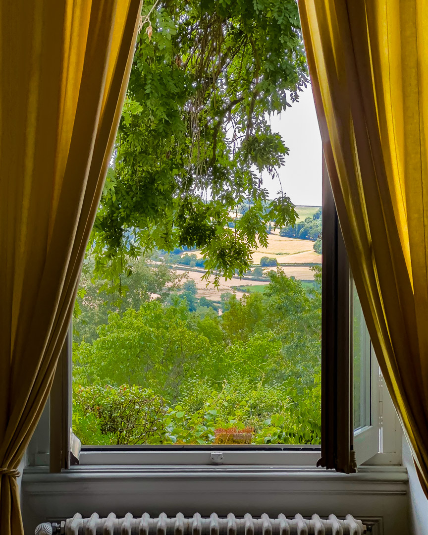 Vue dominante sur la vallée depuis les hautes fenêtres du salon d'une maison bourgeoise du XVIIIᵉ siècle dans le Clunisois.