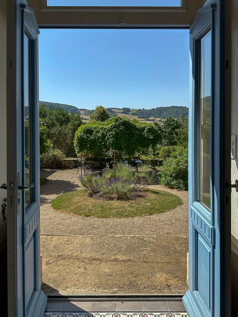 Vue depuis le coulir d'une maison bourgeoise du XVIIIᵉ siècle sur un jardin clos en terrasses avec vue dominante sur la vallée du Clunisois.