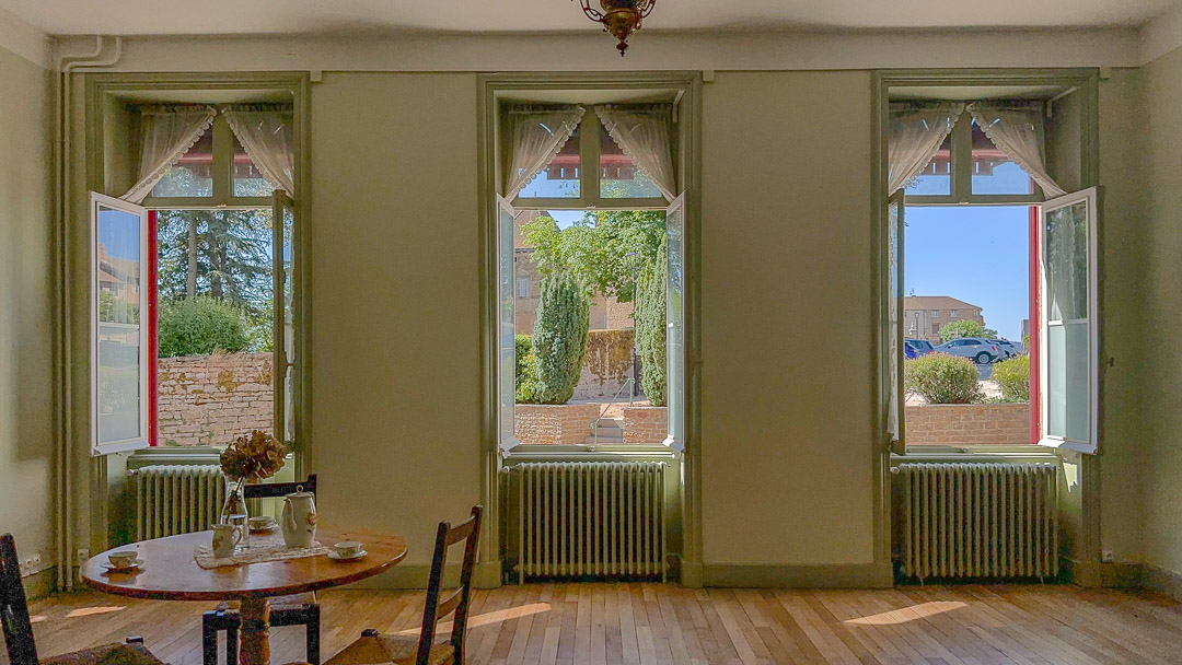 Grand salon rénové avec parquet ancien, cheminée et hautes fenêtres dans une demeure bourgeoise à Tramayes.