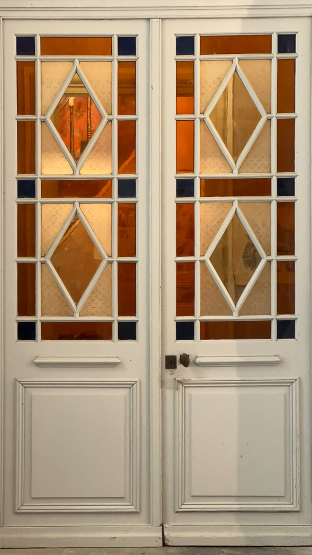 Porte en bois avec vitrages colorés et motifs géométriques dans une demeure bourgeoise à Tramayes.