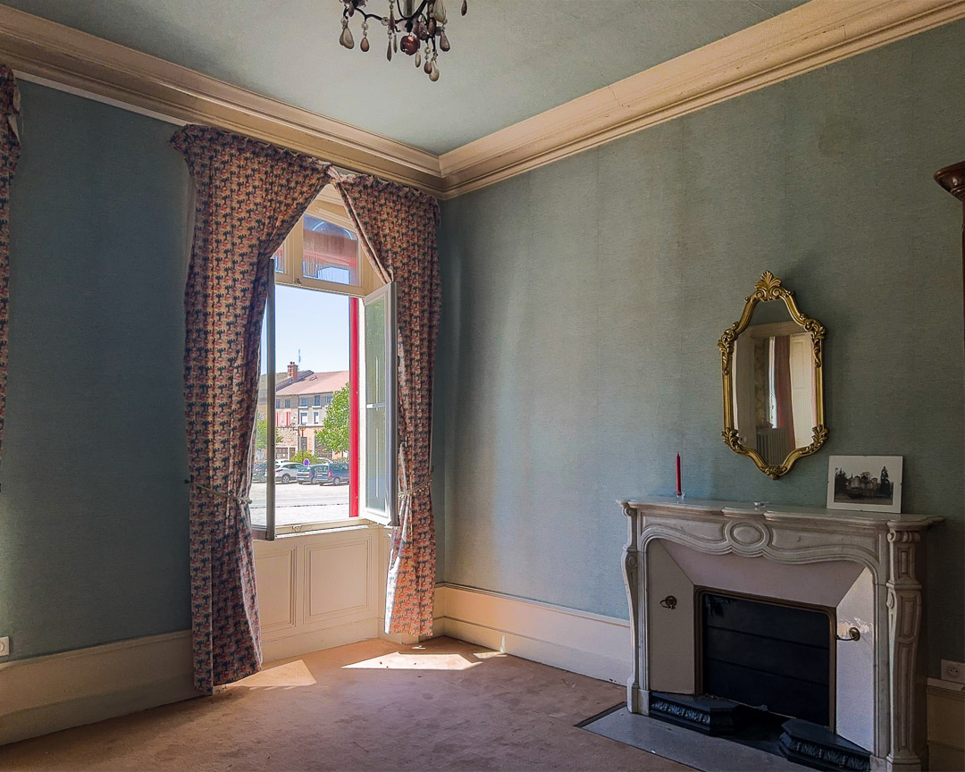 Salon avec cheminée en marbre, hauts plafonds et grande fenêtre dans une demeure bourgeoise à Tramayes.