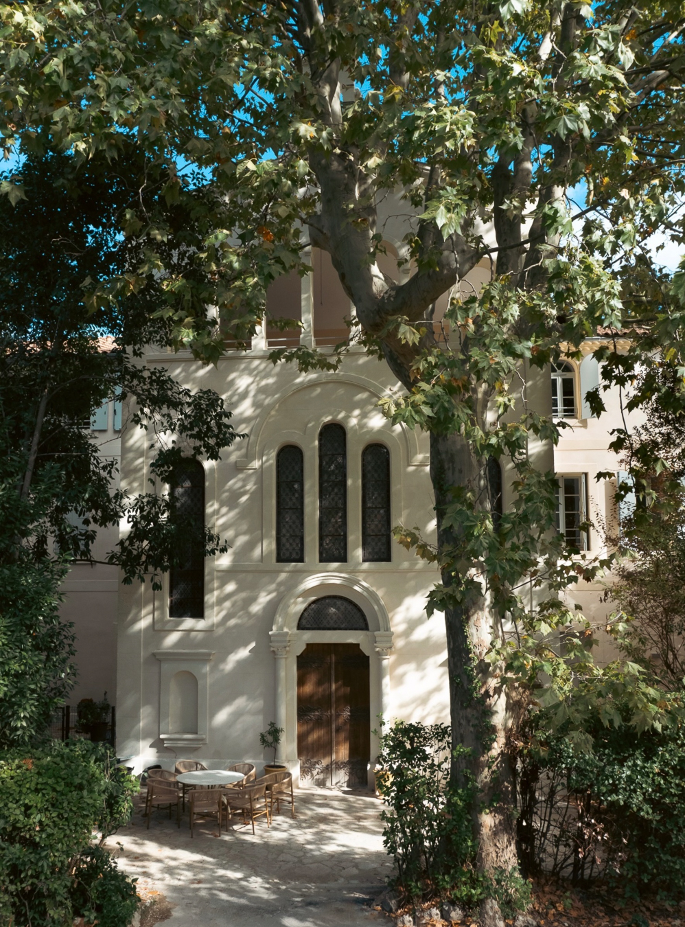 Façade d’une ancienne chapelle entourée d’arbres avec terrasse ombragée dans le quartier Boutonnet à Montpellier.