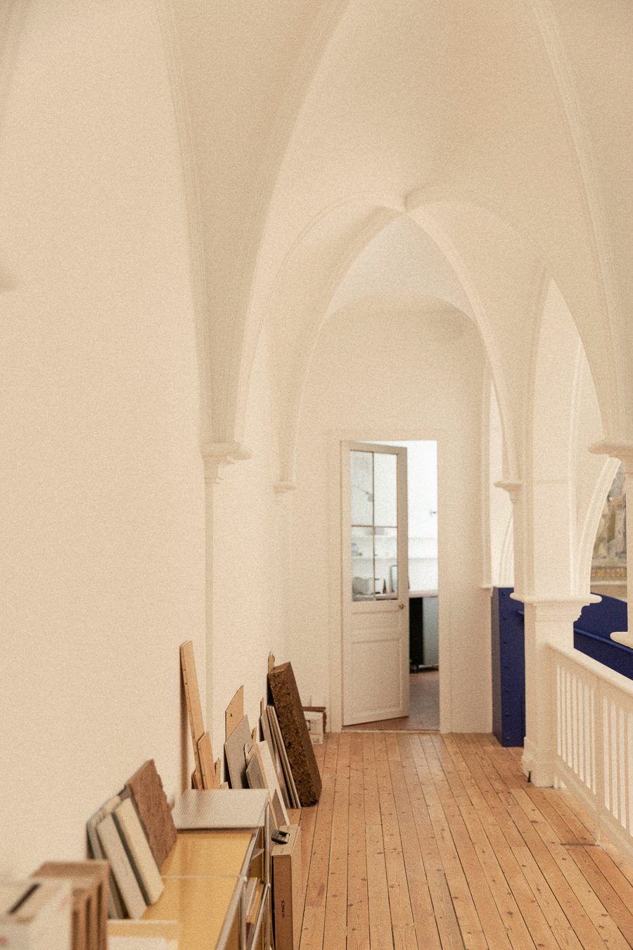 Coursive voûtée avec parquet à l’étage d’une ancienne chapelle réhabilitée à Montpellier, menant vers la cuisine et les espaces d’eau.