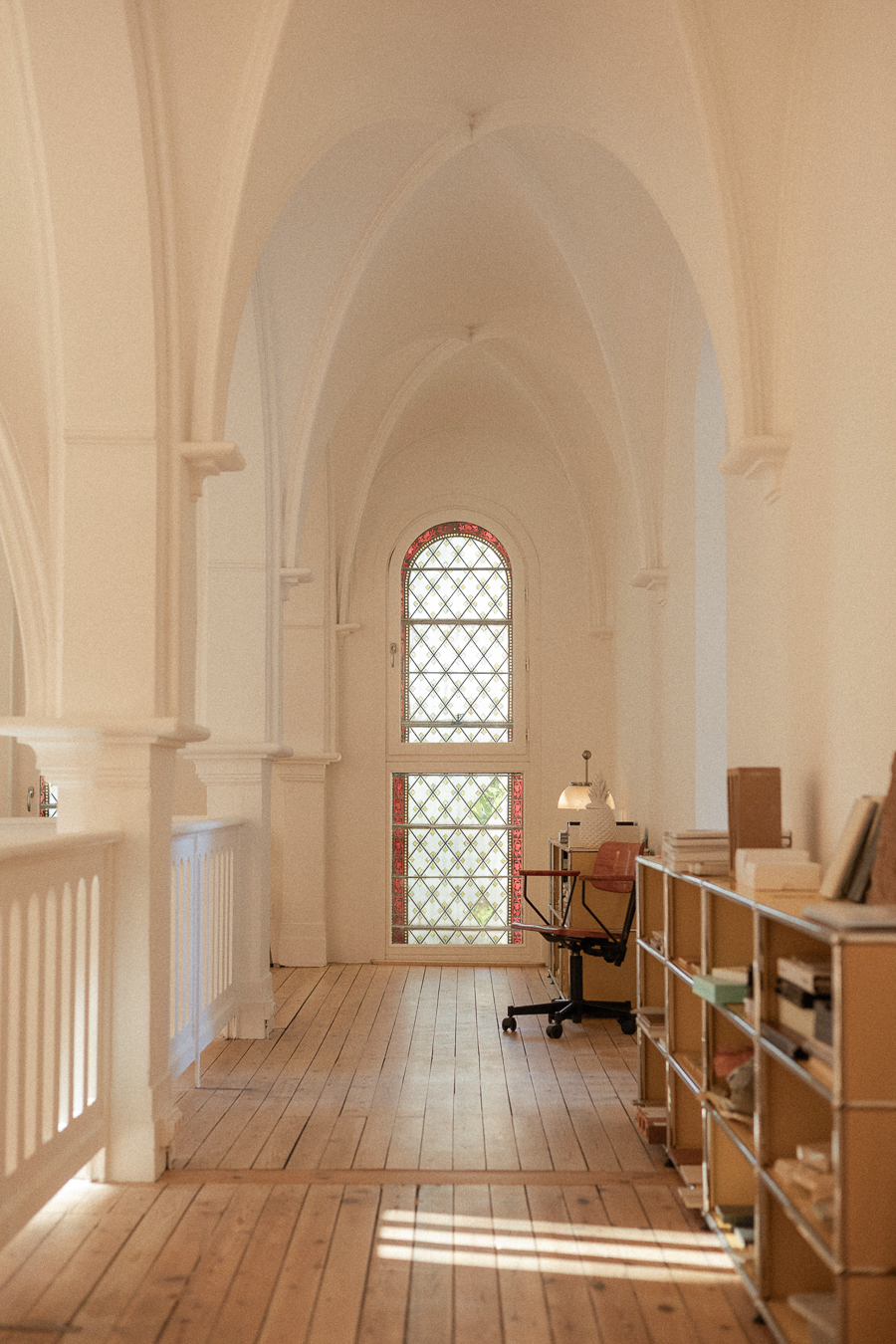 Coursive voûtée en parquet éclairée par un grand vitrail et un rayon de soleil dans une ancienne chapelle à Montpellier.
