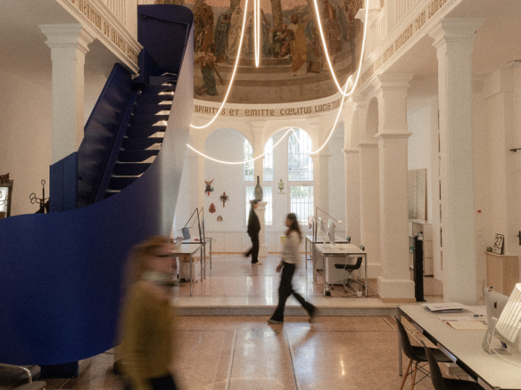 Grande nef voûtée d’une ancienne chapelle à Montpellier avec fresque, escalier bleu, suspension lumineuse et silhouettes en mouvement.